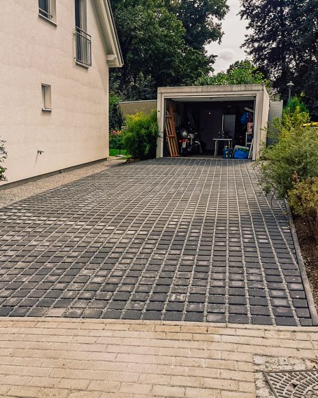Klimaanpassung im Alltag – versickerungsfähige Pflasterung für private Flächen Mit Betonpflaster gepflasterte, wasserdurchlässige Hofeinfahrt vor Garage